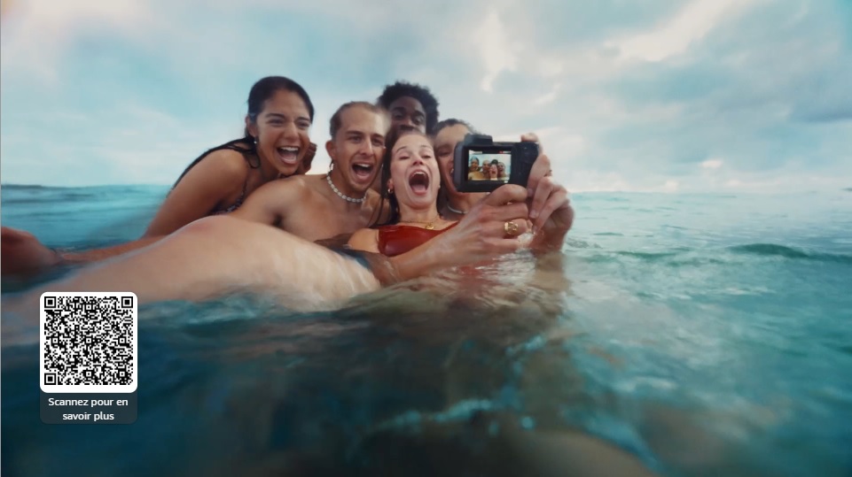 Screenshot of an ad where a group of swimmers in the sea take a group selfie with a camera